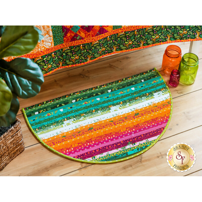 Colorful half-moon rug features vibrant stripes of green, orange, pink, and white, placed on wooden floor.