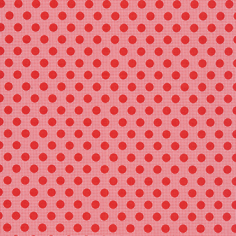 Pink sewing fabric with reddish orange polka dots all over
