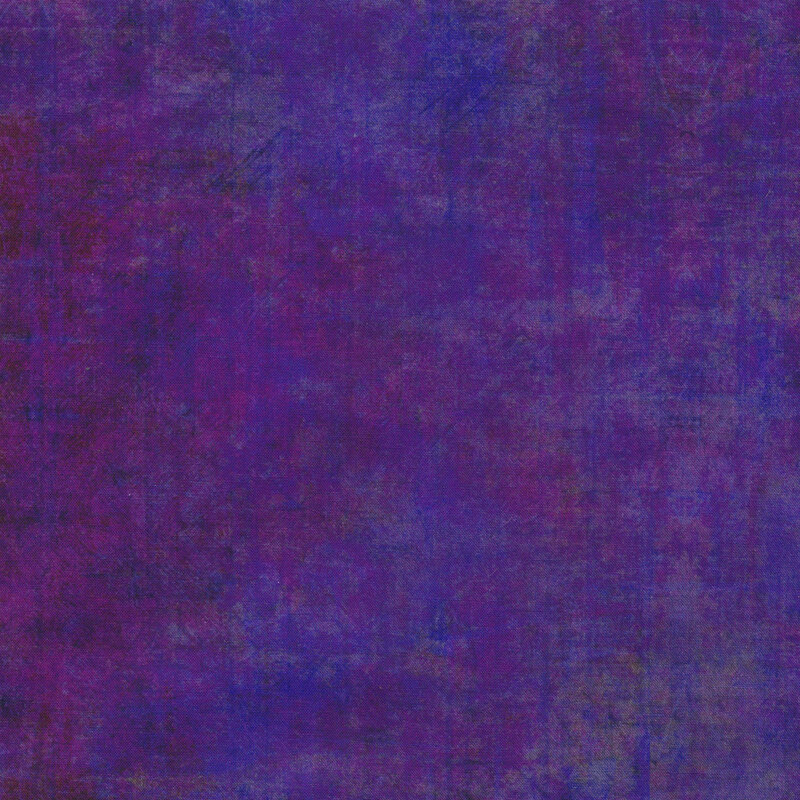 A mottled dark purple fabric with a grunge texture look with bits of blue and dull oranges peeking through