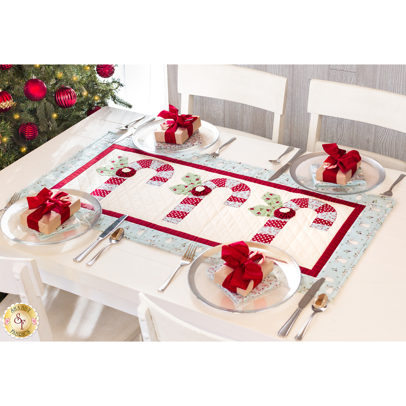 Red and white table runner featuring 3 candy canes with fabric yo-yos, all made of Winter themed fabric prints.