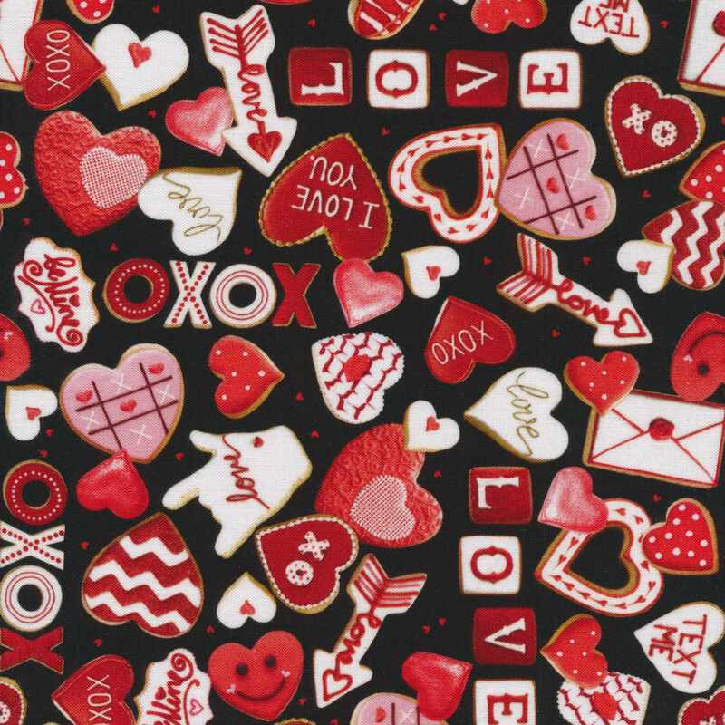 Black fabric with heart shapes and valentine's day themed cookies tossed all over