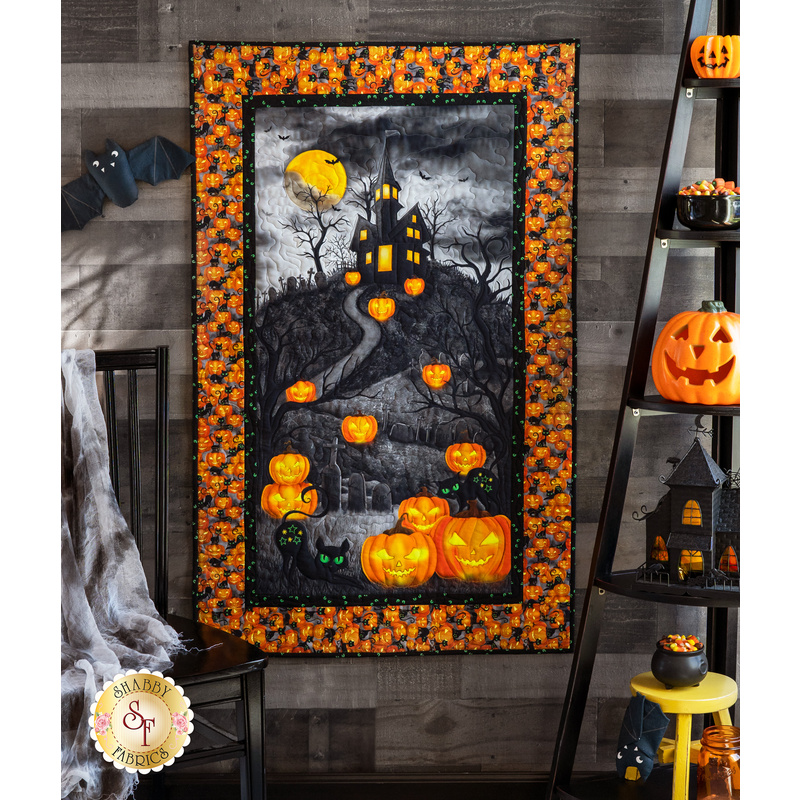 Panel quilt featuring a scene of a dark gothic house on a hill with cats and jack-o-lanterns under a yellow moon.