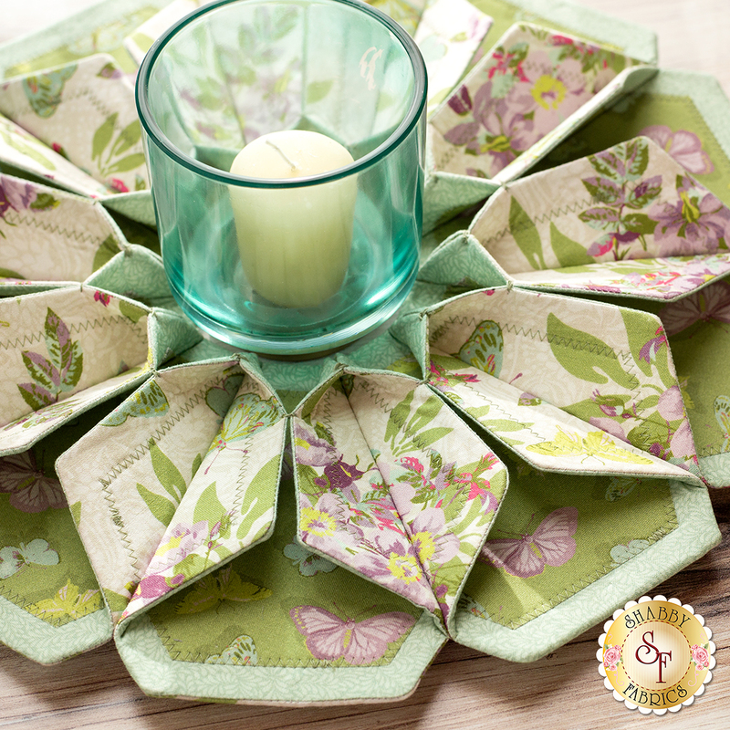 10 sided folded wreath being used as table topper with candle in the middle made of green and purple floral fabrics.
