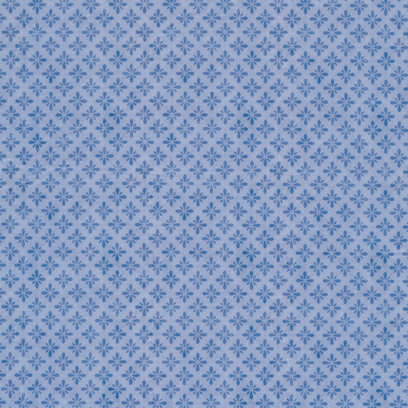 Tonal blue fabric with small emblems evenly spaced all over in a burst or floral shape