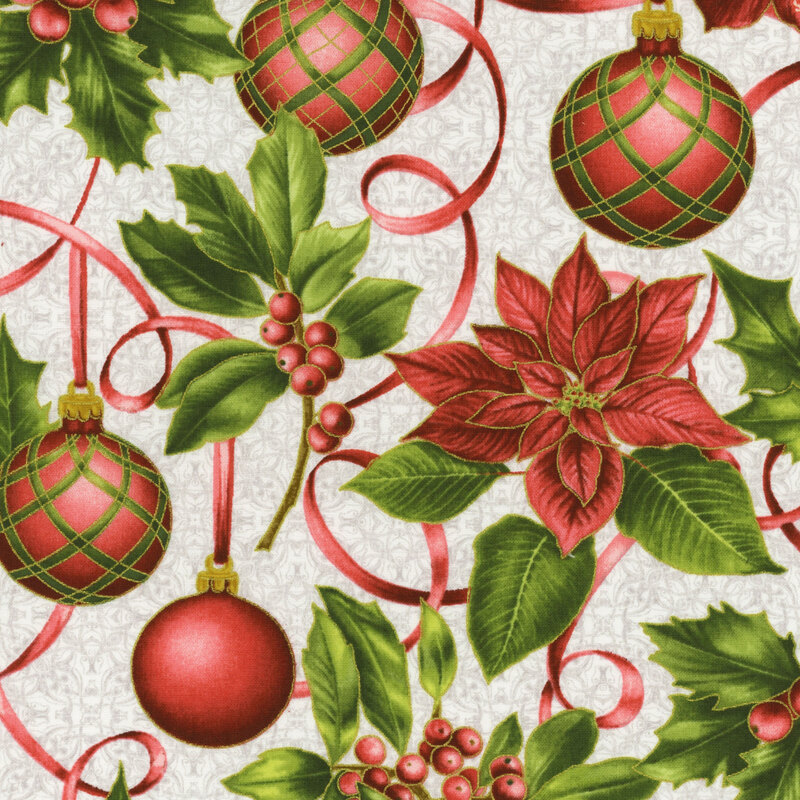 Green holly and berries, red poinsettias, and Christmas ornaments on a white fabric background
