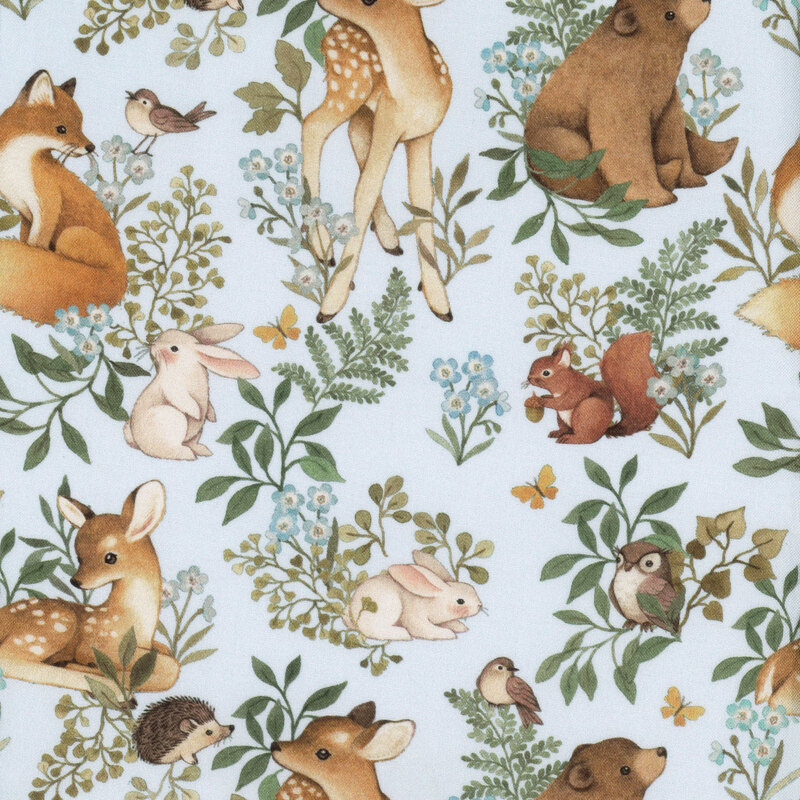 Pale blue fabric with woodland creatures and green ferns and plants all over