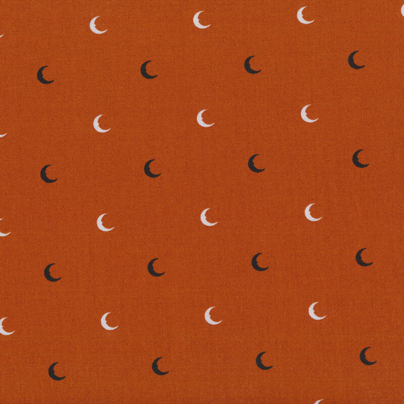 dark burnt orange fabric with black and white crescent moons evenly spaced all over