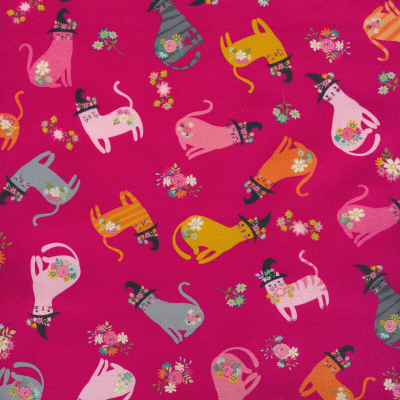 Bright pink fabric with a variety of tossed colorful cats wearing witch hats.