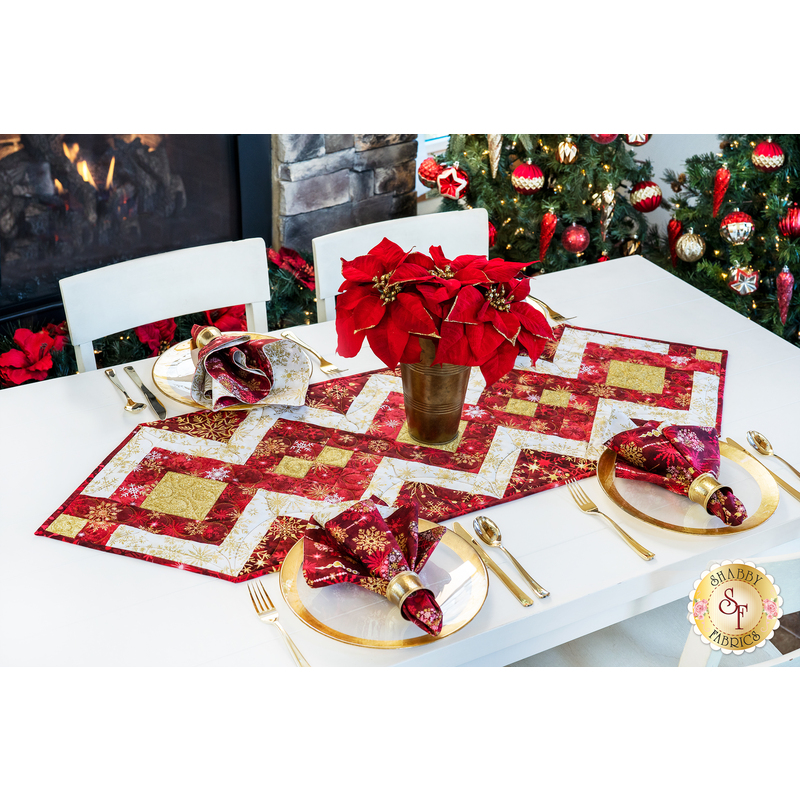 Table runner with strips of fabric in a lattice design made from metallic red and cream Christmas and snowflake printed fabrics.