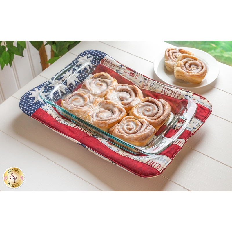 An image of an Americana Casserole Hot Pad with a casserole dish of cinnamon rolls on a white table.
