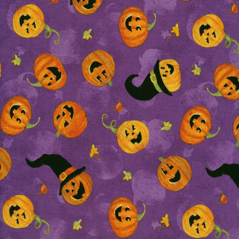 Purple fabric with tossed jack-o-lanterns with witch hats and small autumn leaves