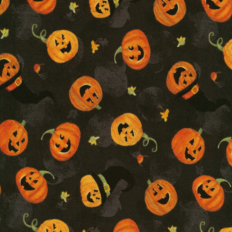 Black fabric with tossed jack-o-lanterns with witch hats and small autumn leaves