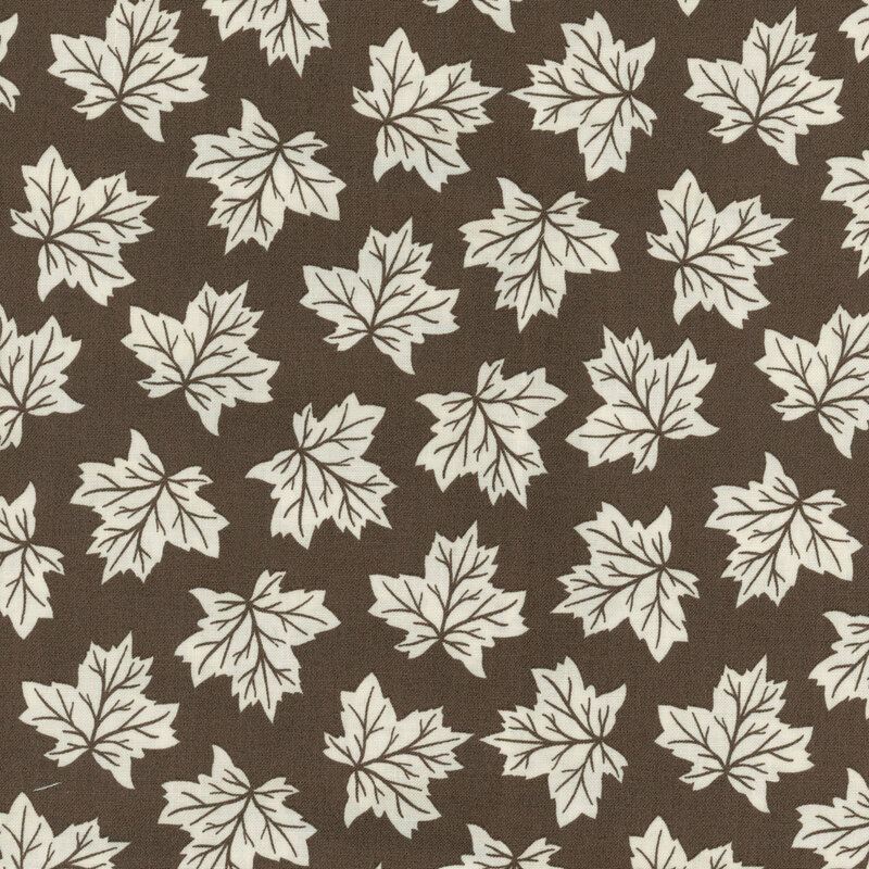fabric featuring tossed off white maple leaves on a brown background