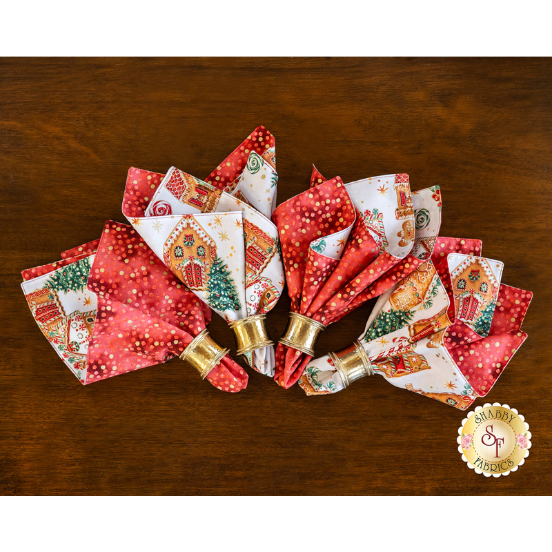 Red and white christmas napkins in gold napkin rings arranged in a fan on a brown wooden background