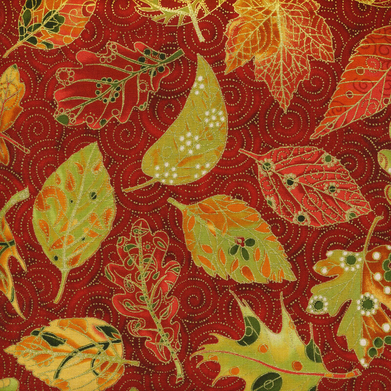 Bright red fabric featuring metallic swirls and yellow and red stylized leaves tossed in the foreground.
