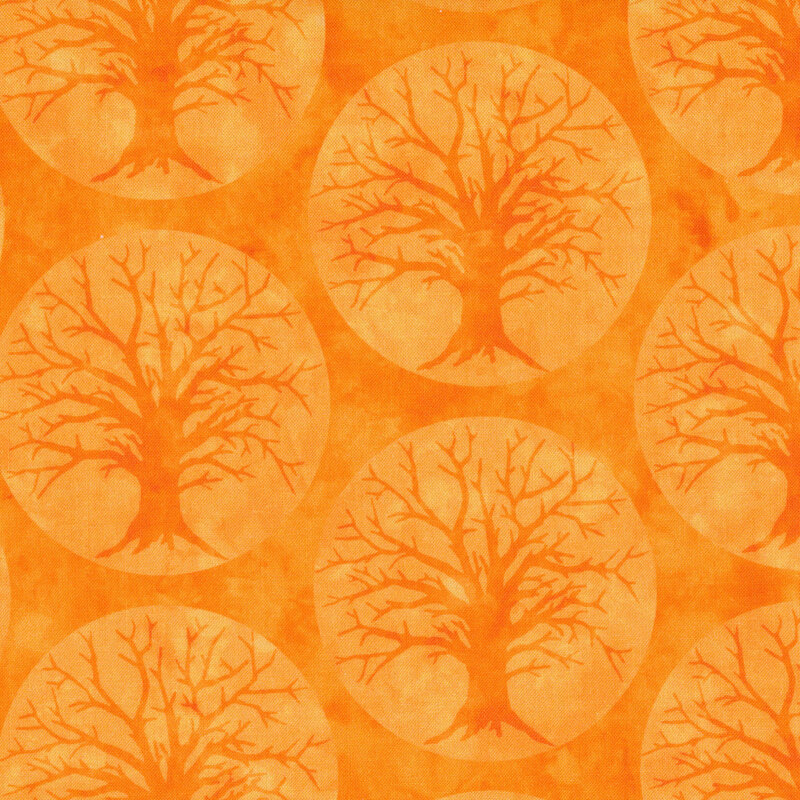 Orange fabric with large pale orange circular moons and silhouettes of scary trees on a darker orange background