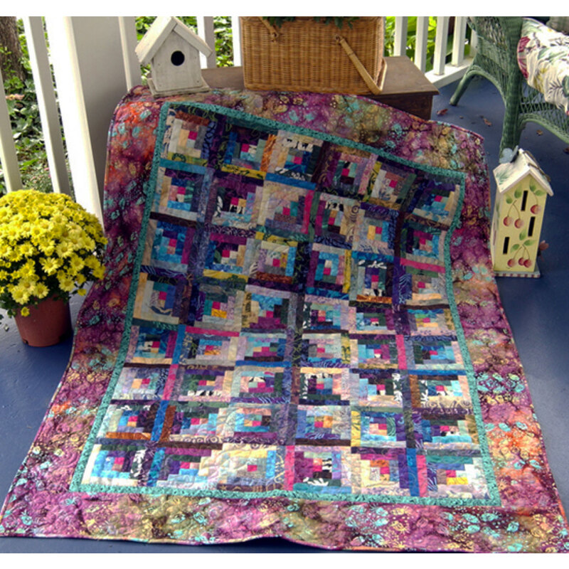 A geometric colorful quilt next to a bright yellow bouquet of flowers