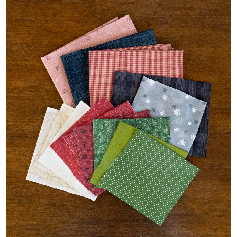 A stack of colorful fabrics included in the Bringing Home the Tree Finishing Kit