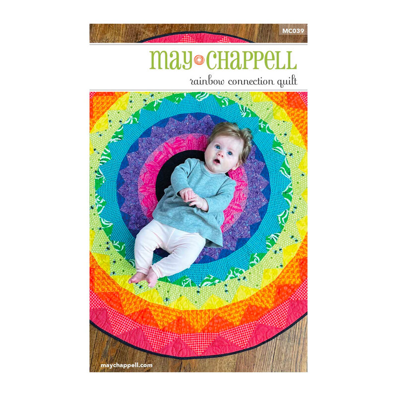 Front of pattern booklet showing completed rainbow round quilt with a baby laying in the middle
