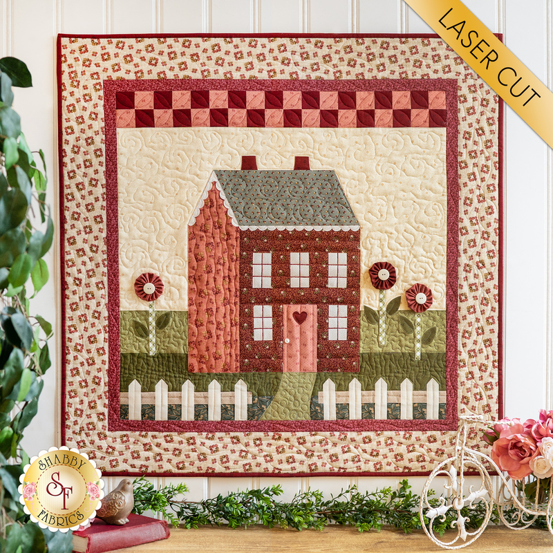 Quilt depicting a spring scene of a house in the middle of a field of red and pink flowers.