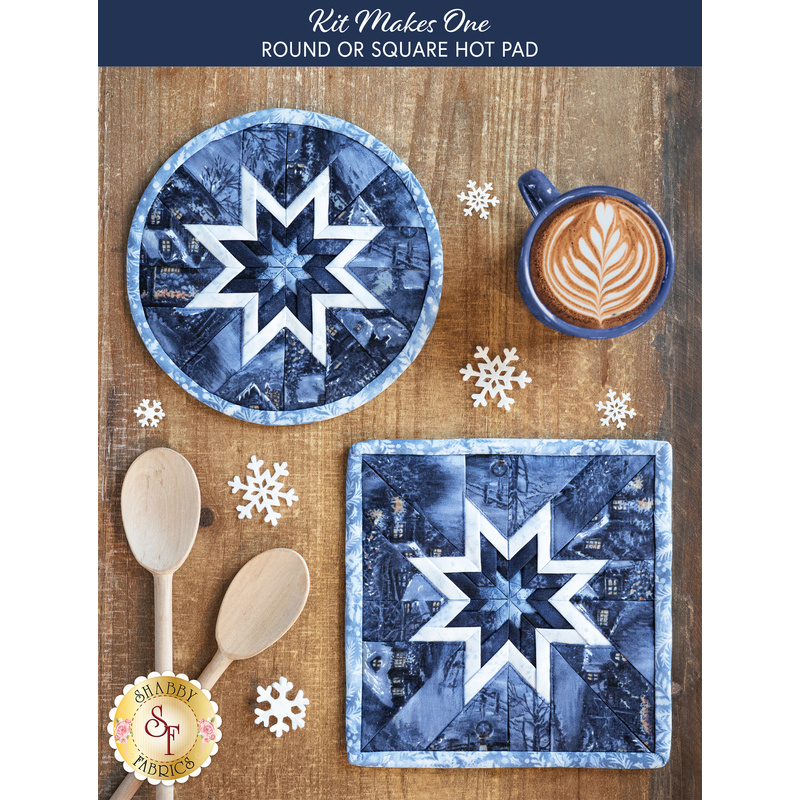 Top down image of two blue hot pads made with the Blizzard Blues collection on a brown wooden table with a cup of hot cocoa, two wooden spoons, and snowflake decorations scattered all over.
