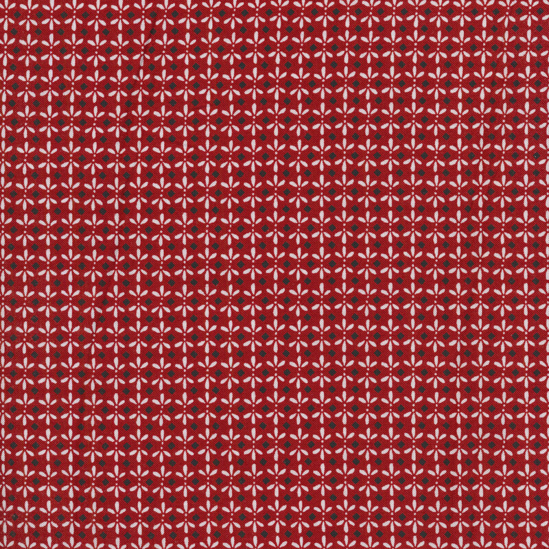 A Christmas red fabric with small black diamonds surrounded be white ornamental designs