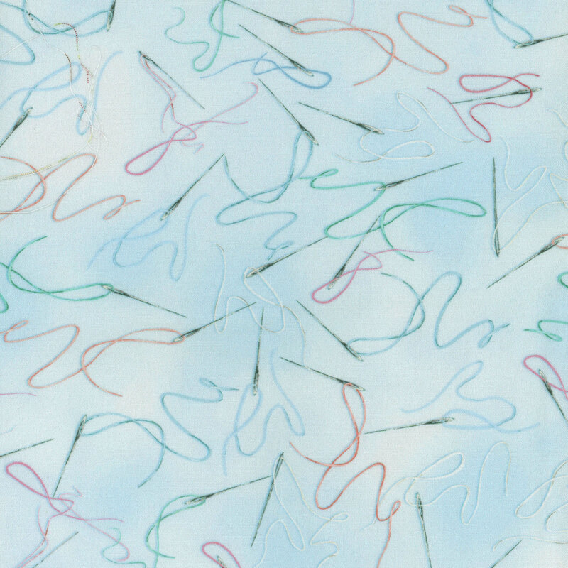 Pale blue mottled fabric with threaded needles tossed all over with different thread colors strewn around them