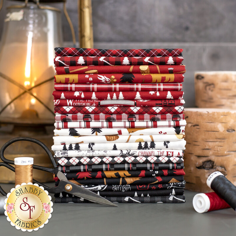 fabric stack, in colors ranging from red to cream to black, next to coordinating threads and in front of a gas lantern and birch log cuttings