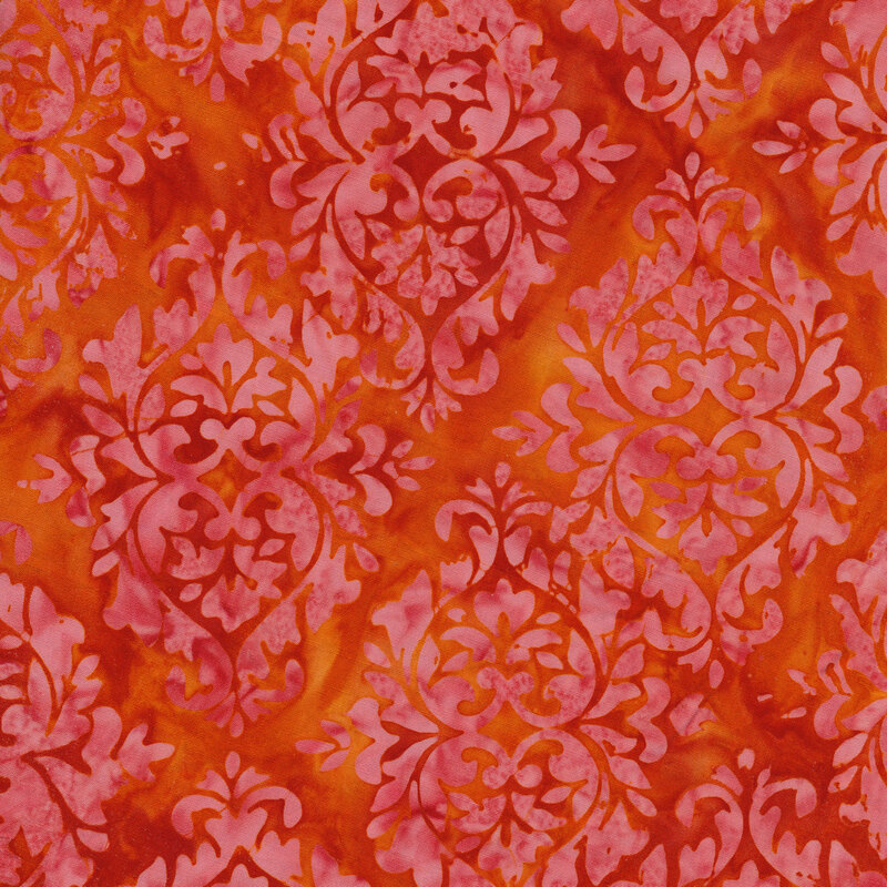 Bright red and orange mottled fabric with damask patterns mottled with shades of hot pink
