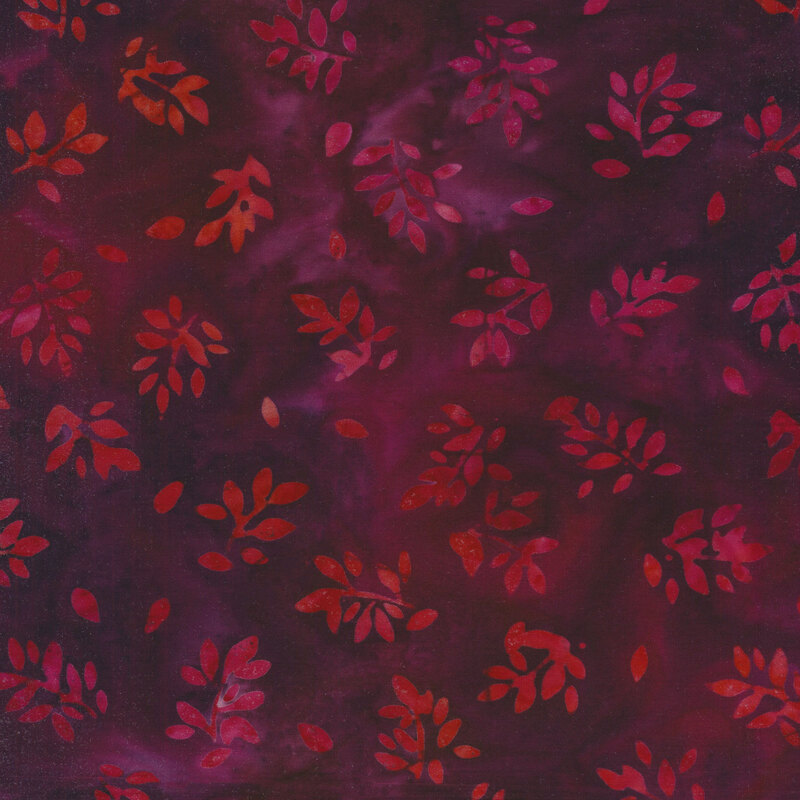 Fabric with red and pink tossed branches with leaves on a dark magenta mottled fabric