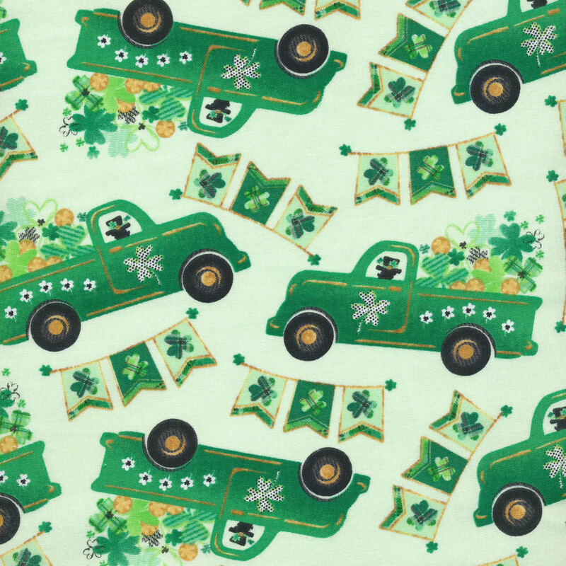 light green fabric with dark green trucks and shamrocks and shamrock banners scattered across it