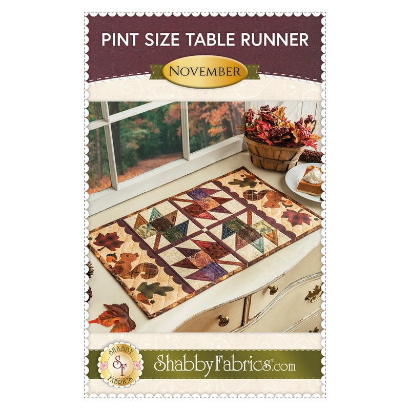 front cover of pint size table runner for the month of November featuring quilted patchwork autumn leaves and squirrels on either end.