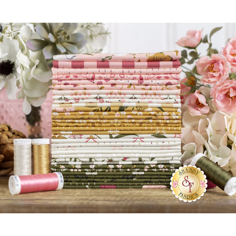 Evermore fat quarter, on a wood table surrounded by pink and cream flowers.