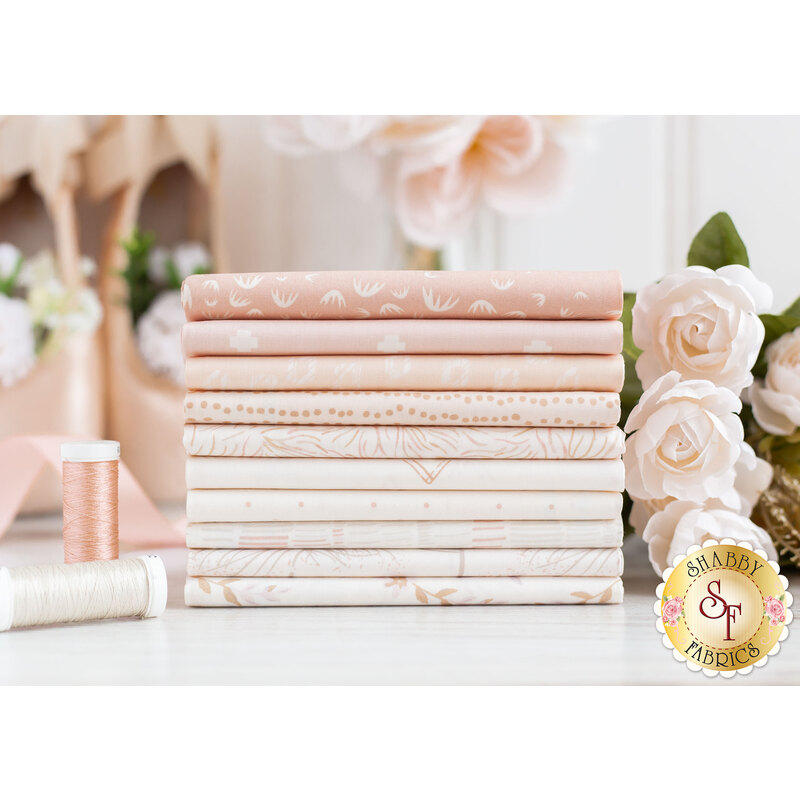 Photograph of the fabrics included in the Ballerina Fusion fat quarter set, set on a white marble countertop and staged with light pink roses, ballet slippers, and coordinating spools of thread.