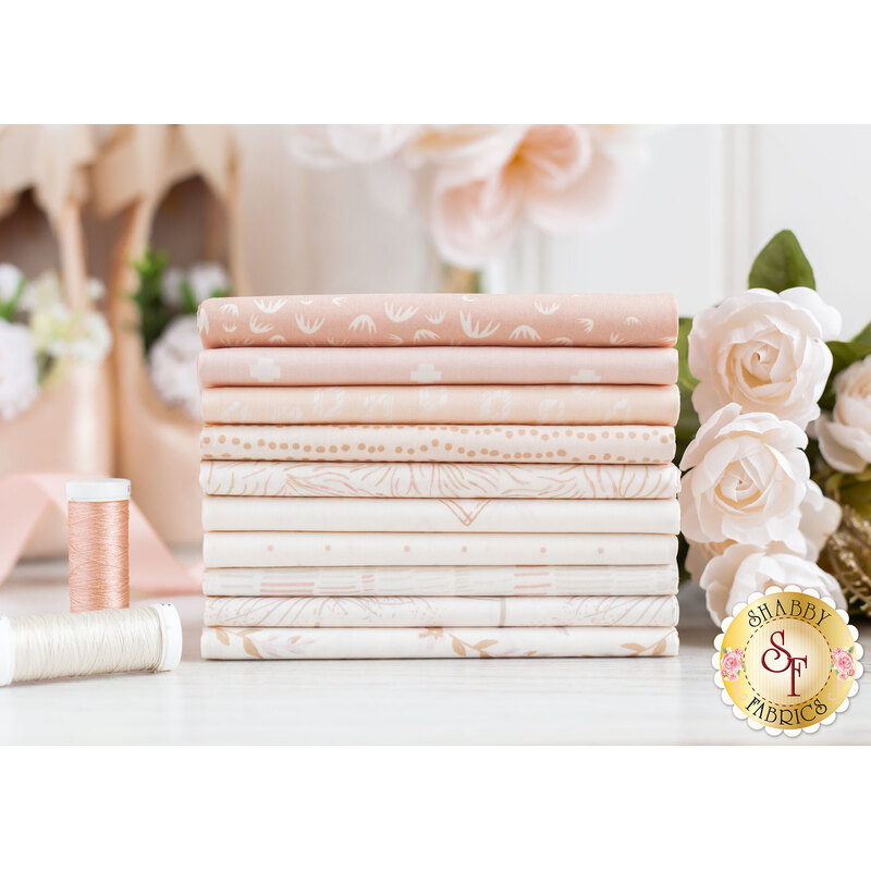 Photograph of the fabrics included in the Ballerina Fusion fat quarter set, set on a white marble countertop and staged with light pink roses, ballet slippers, and coordinating spools of thread.