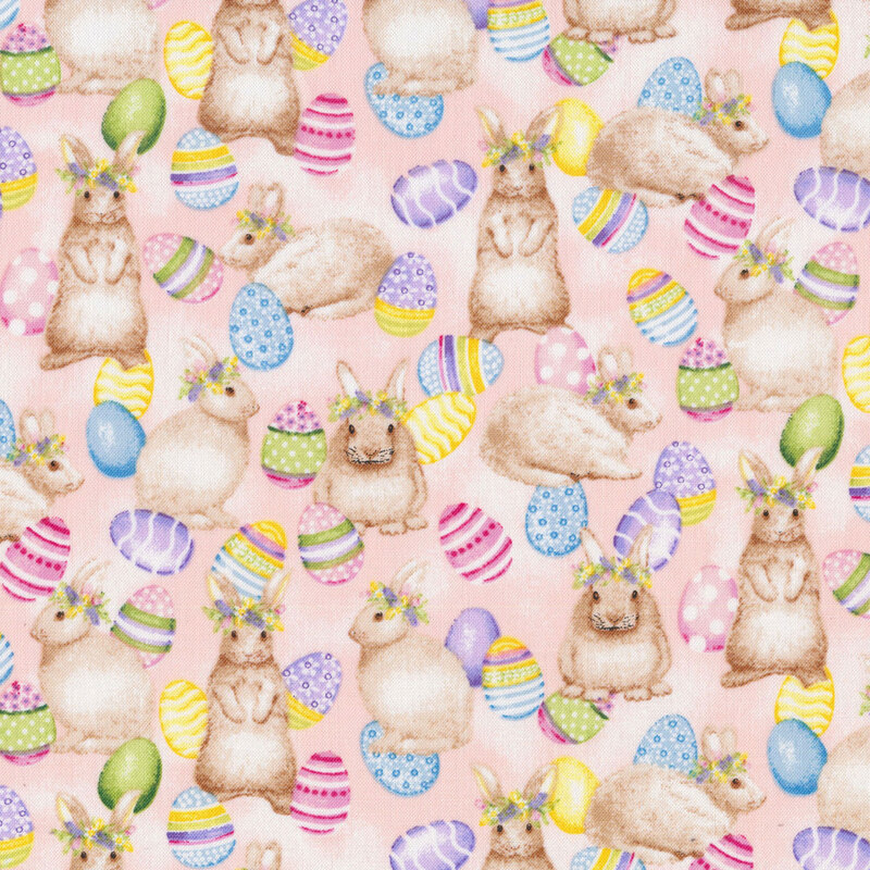 This fabric features light brown bunnies with flower crowns surrounded by bright colorful easter eggs on a mottled pink background.