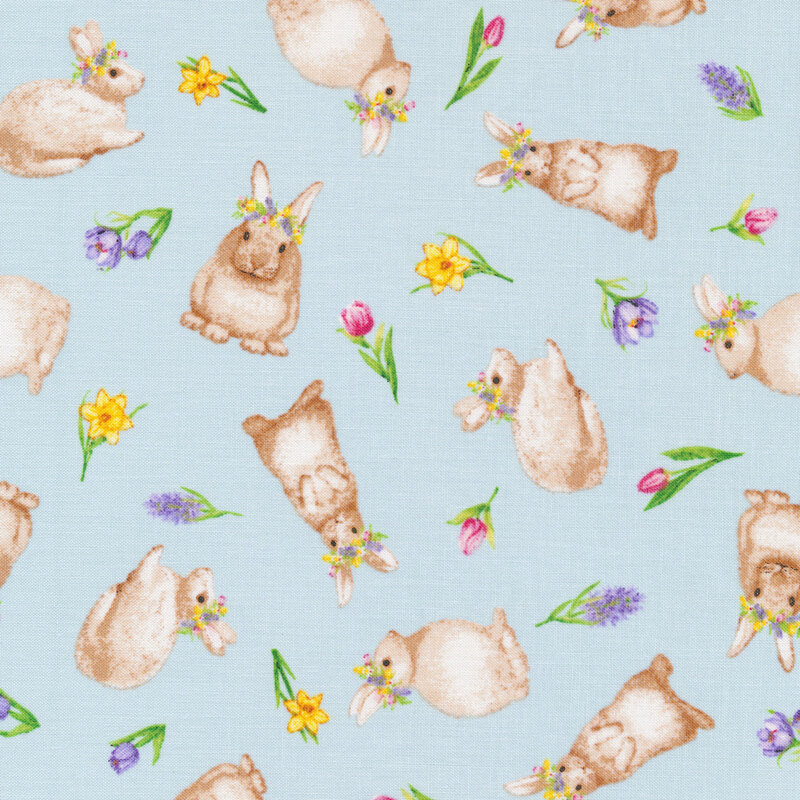 This fabric features tossed bunnies with flower crowns and tossed spring flowers on a pastel blue background.