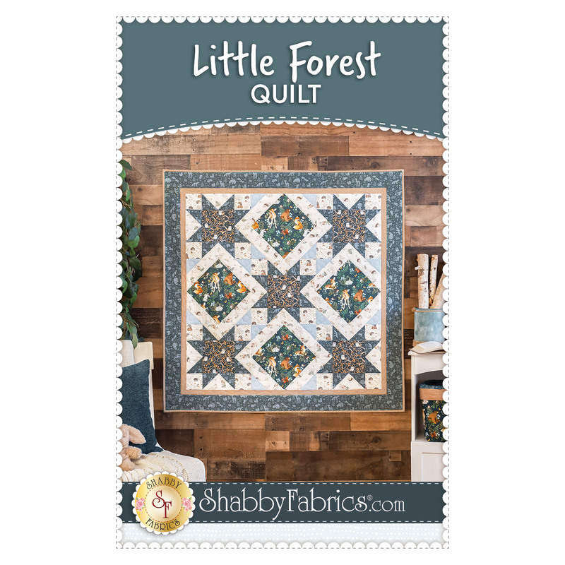 Photo of finished Little Forest Quilt hanging on a wood paneled wall with the title, 