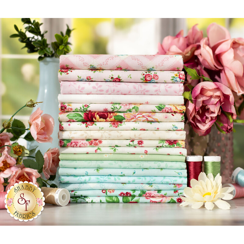Pink, cream, green and blue floral fabrics on a wood table surrounded by flowers
