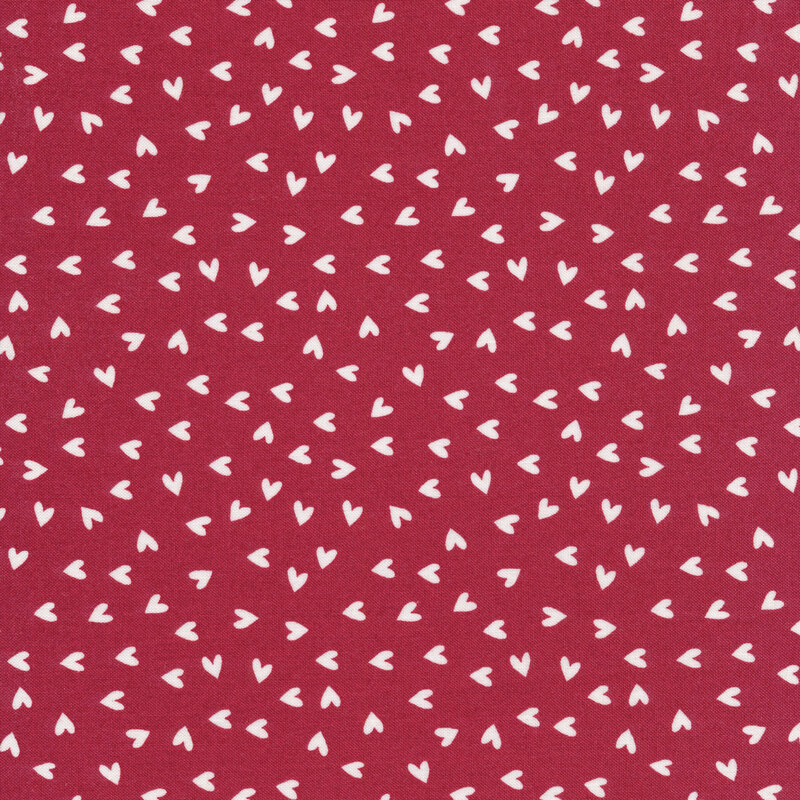 This fabric features white ditsy tossed hearts on a red background.