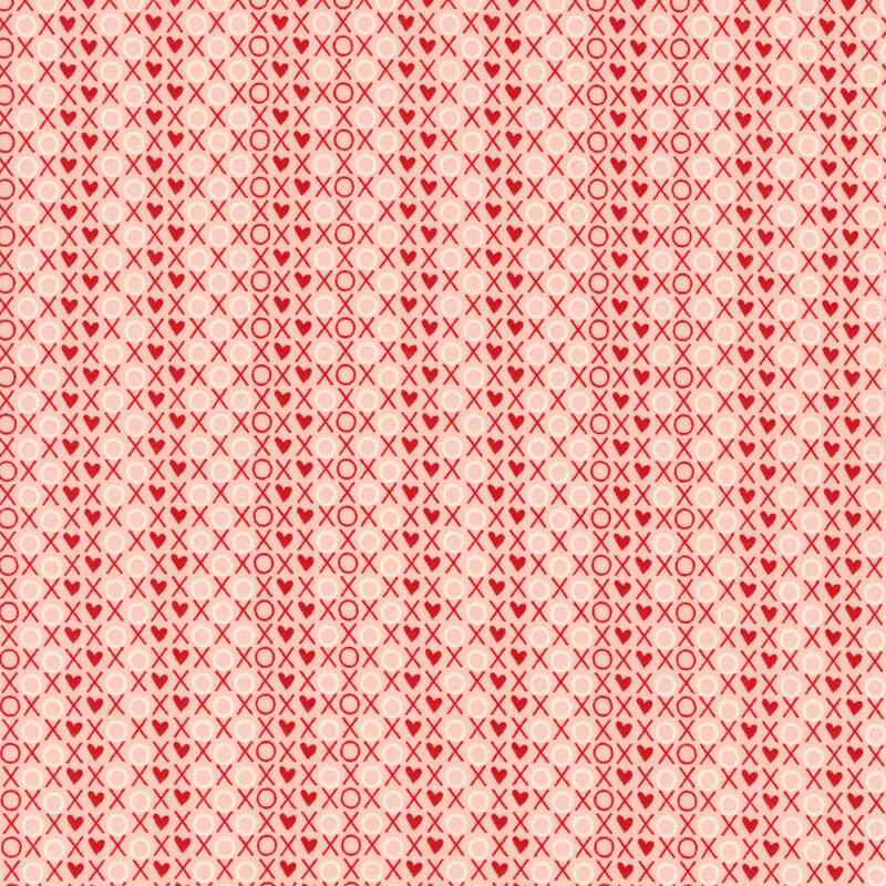 fabric featuring a packed print of XOXO words and hearts in red and white on a light pink background