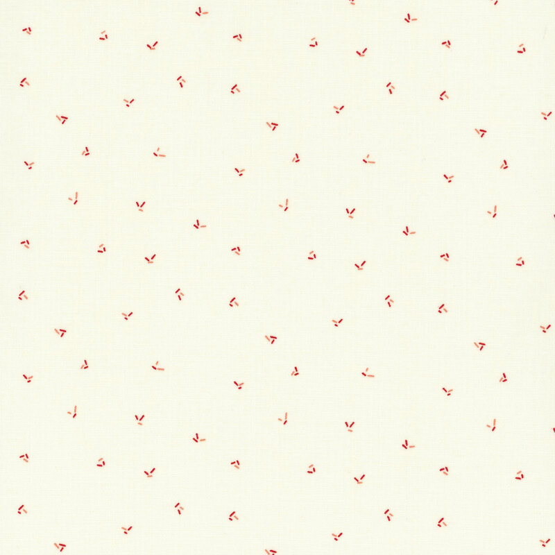 fabric featuring ditsy red and pink sprinkles on a solid cream background