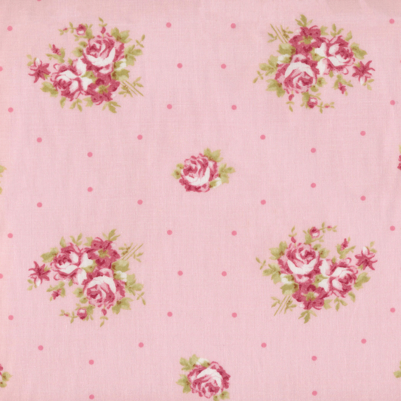 Image of fabric featuring arrangements of pink flowers and roses, interspersed with darker pink dots, on a lighter pink background