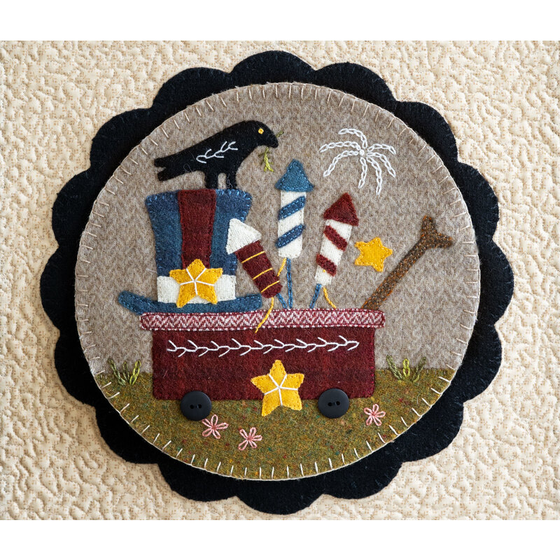 Image of a center circle mat for the Welcome Home wall hanging, featuring a playful crow on a wagon full of fireworks crafted from wool 