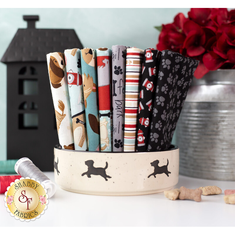 dog themed white, grey, black, and teal fabrics stacked inside a dog bowl
