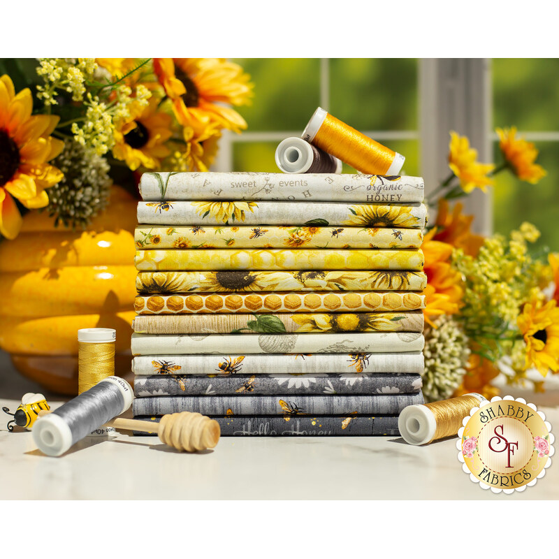 A photograph of stacked yellow, gray, and white fabrics in the Honey Bee Farm One Yard Set