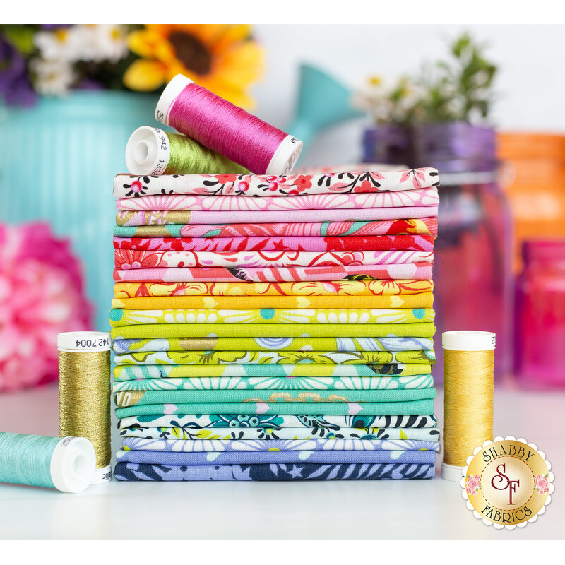 Vivid rainbow of colorful fabrics stacked with coordinating threads, with colorful florals and jars in the background