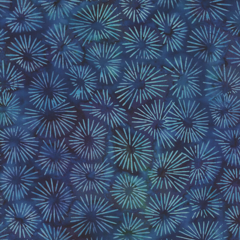 A dark blue and aqua mottled batik fabric with bright aqua sun burst designs