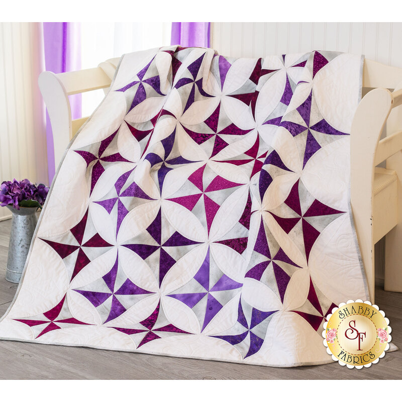 Draped quilt with white background fabric and purple pinwheels
