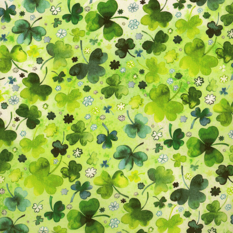 Scan of fabric featuring tossed three-leaf clovers in various sizes and shades of green, interspersed with tiny flowers, and set against a cloudy light green background
